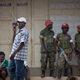 In this Saturday, Feb. 20, 2016 file photo, a man walks past listening to news on a portable radio as military police deploy, shortly after the election result was announced, and social media had been blocked, in downtown Kampala, Uganda.